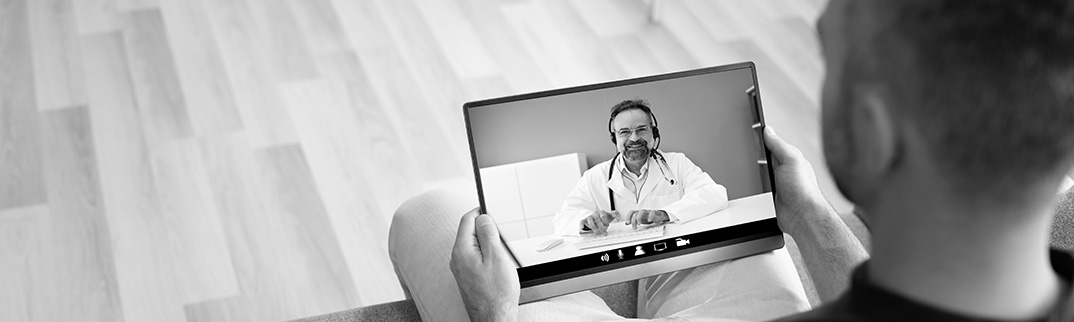 A man sitting on a couch having a telehealth visit on his tablet