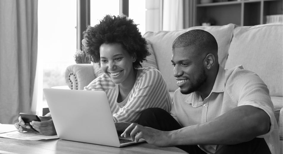 A smiling couple sits together looking at a laptop