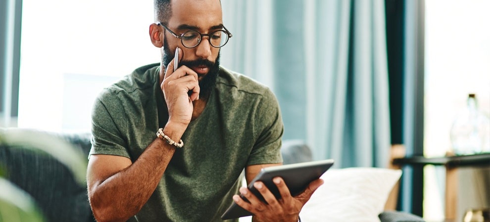 A man with glasses looks at his tablet