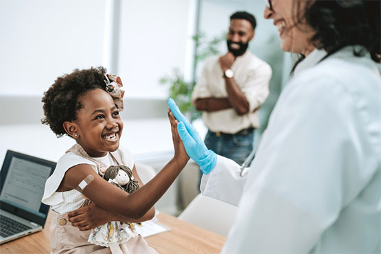 A child high fives her doctor after getting a vaccine