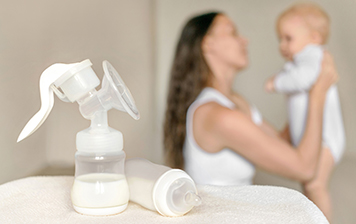A bottle of breast milk and a breast pump with a mother and her baby.