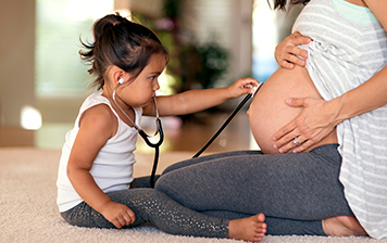 A child listens to a mother's pregnant belly