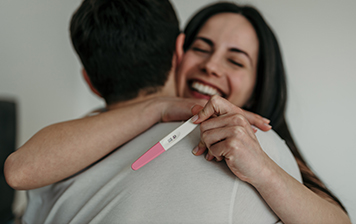 A couple hug after looking at their pregnancy test together