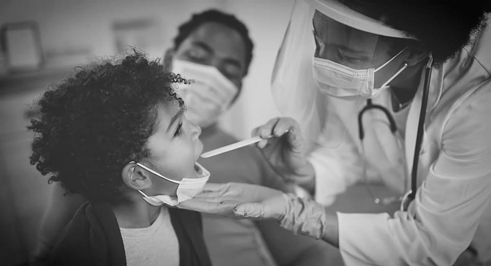 A doctor uses a tongue depressor to check a child's throat.