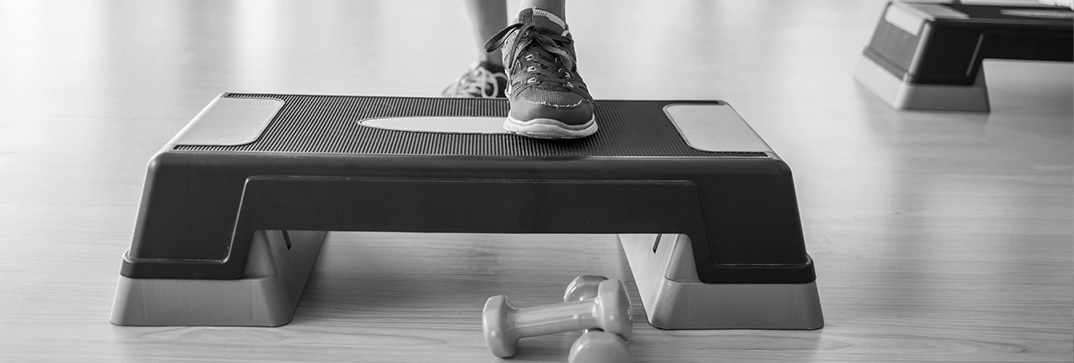 woman stepped up on step board during fitness class