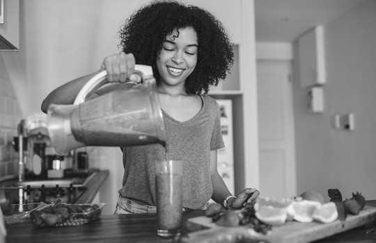 A woman making a healthy smoothie at home.