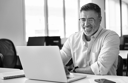 A man smiles while looking at his account online. 