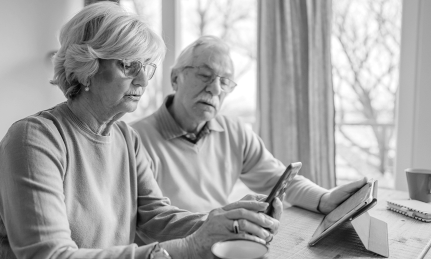 An elderly couple looking at a mobile device together