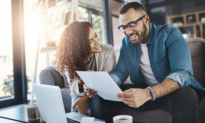 Two people sitting at home looking at paperwork together.