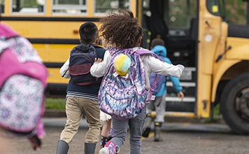 Children run to catch the school bus. 