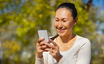 A woman smiles while watching video on her phone.