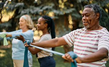 A senior man uses a resistance band during an exercise class. 