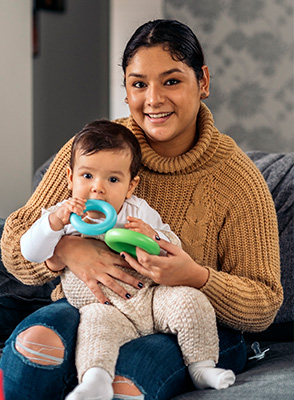 A woman sits and holds a baby on her knee.