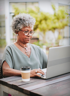 A woman with glasses types on her laptop and registers for a Blue Cross online account.